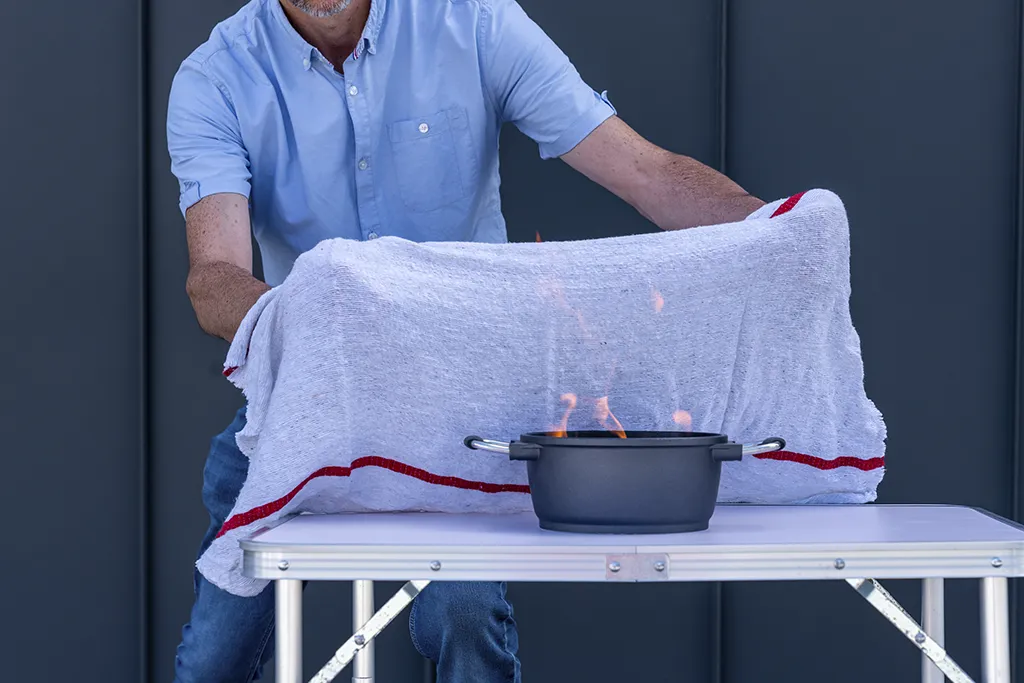 Extinction d’un feu de casserole avec une couverture anti-feu lors d’une formation incendie