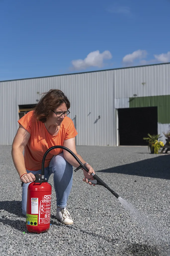 Femme utilisant un extincteur lors d’une formation incendie en entreprise