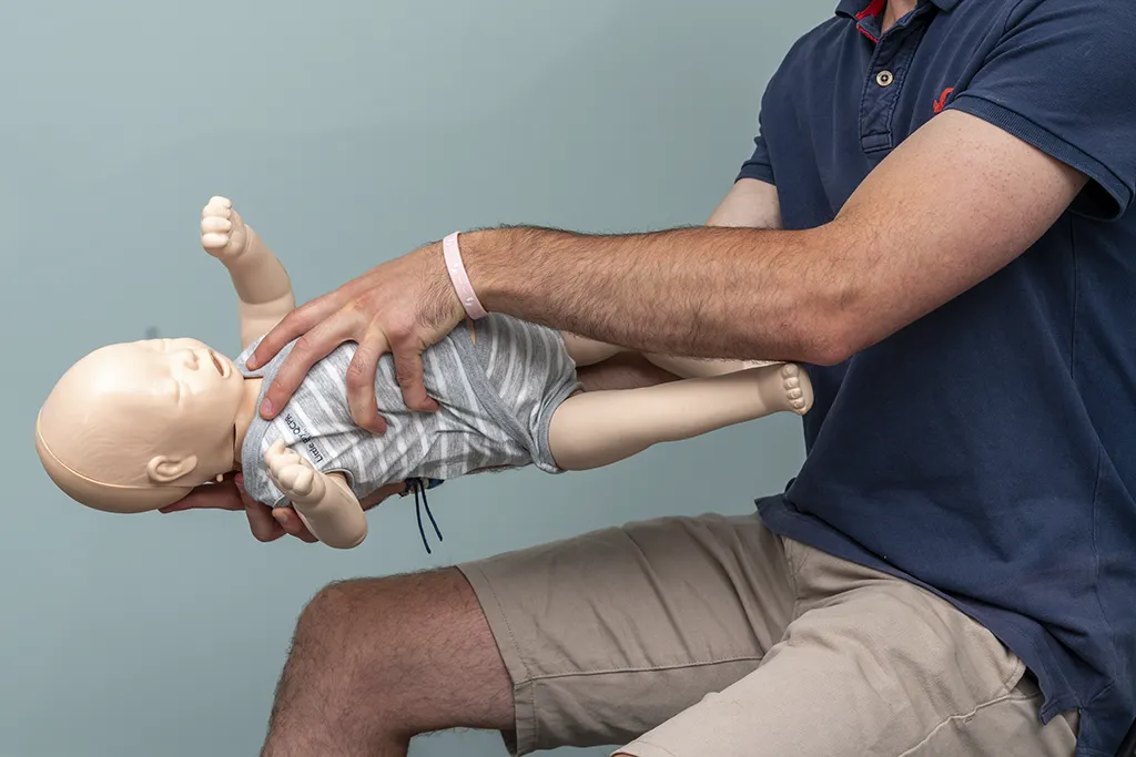 Formateur SST montrant une manœuvre de secours sur un mannequin bébé