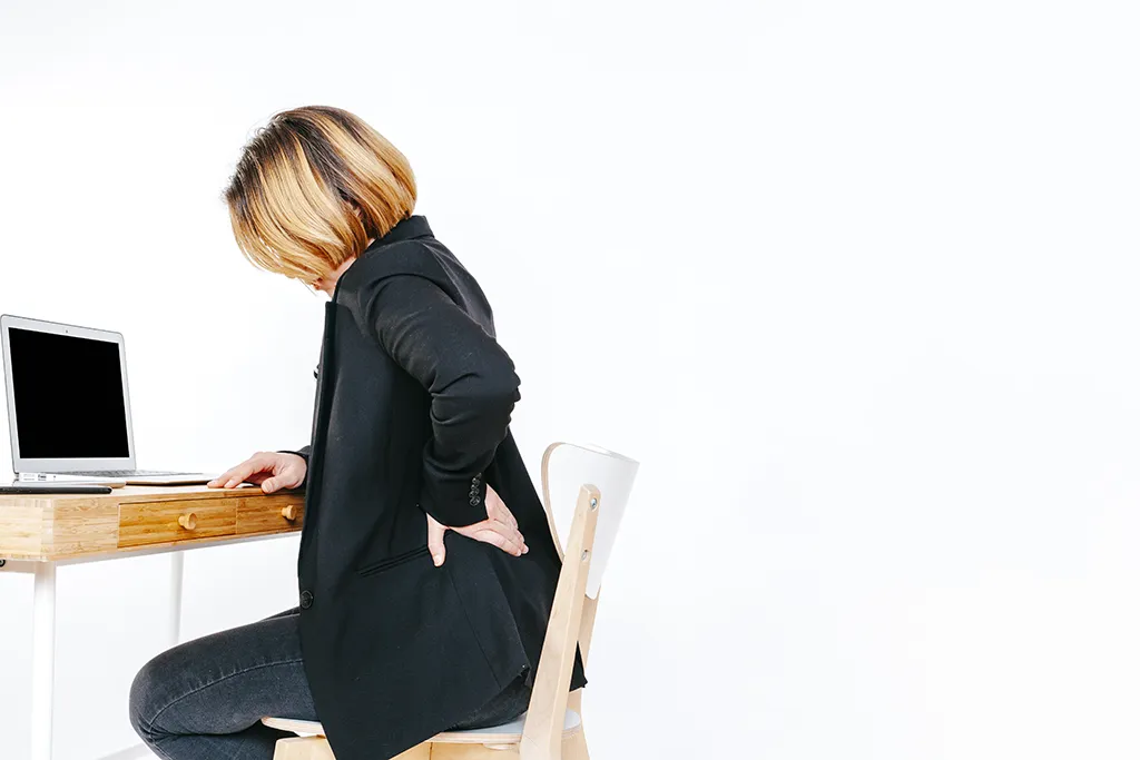 Femme assise devant un ordinateur souffrant de douleurs dorsales